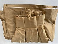 Folded gold silk drapery panels showing pleated heading and lining