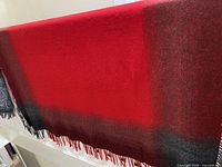 Full view of red throw with black border and fringe