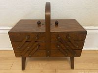 full view of closed wooden cantilever sewing box on legs