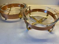 Two Pyrex dishes seated in brass and copper frames