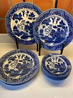 Group view of all eight blue and white porcelain plates, four dinner and four dessert sizes