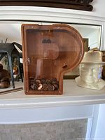 Front view of wooden P-shaped coin bank on shelf