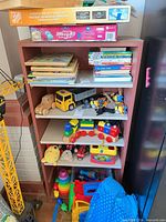 Front view of painted wood bookshelf loaded with toys illustrating structure and condition