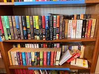 Two shelves tightly packed with paperback novels, spines outward