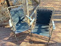 Two matching navy sling folding patio chairs on brick patio