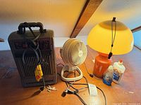 Heater, fan, lamp, glue and soap on table