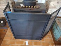 Front view of black metal tri-fold fireplace screen showing center and angled side panels