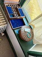 Open dovetailed box showing blue felt compartments and adjacent woven basket with lid and turquoise handle