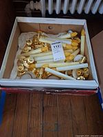 Box containing numerous ivory battery candles with gold bases