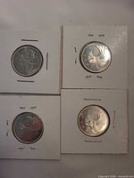 Group of four 1964 Canadian quarters in holders, showing reverse caribou design