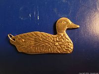Front view of brass duck cutting tool showing engraved feathers and ring