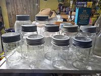 Front view of assorted pint and quart glass canning jars with glass lids and screw bands