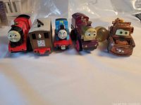 Front view of four Thomas trains, Mater figure and bouncy ball