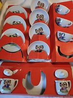 Tray showing four cups, four saucers and two lidded pots set in red cardboard