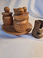Angle view of carved wooden condiment set on tray with boot figurine