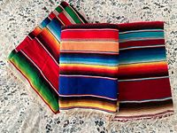 Three folded multicolour serape blankets showing size variation and fringe