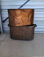 Two stacked copper washbasins showing exterior surfaces and patina