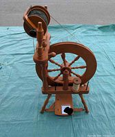 Full view of Ashford spinning wheel standing on mat showing wheel, flyer, treadle and bobbins