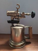 Side view of brass blowtorch showing wood handle, burner assembly and adjustment knob