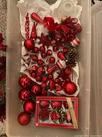Storage bin containing assorted red ornaments and boxed poinsettia clips
