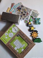 Overall lot layout showing papermaking kit box, transfer sheets, foam stamps, metal tin