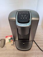 Front view of Keurig brewer with reusable filter and accessory box visible