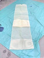 Long cream latch-hook rug canvas laid out on tarp