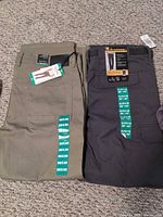 Two pairs of pants laid flat showing size stickers and tags