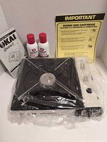 Stove in plastic wrap with instruction booklet, two Ronson butane cans and fixing gas cartridge sheet