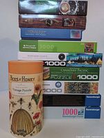 Stack of puzzle boxes and Bees & Honey cylindrical tube showing quantity, brands and piece counts