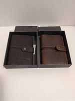 Two leather passport covers in individual RH boxes, dark and medium brown tones