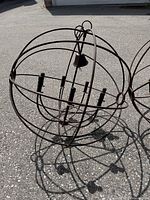 Orb chandelier resting on pavement showing full spherical frame and candle sockets