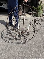 Person holding iron orb chandelier outdoors showing overall structure and candle arms