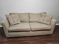 Beige sleeper sofa with two patterned pillows
