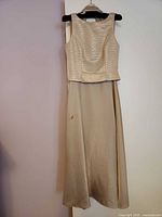 Front view of champagne and gold satin gown hanging on hanger