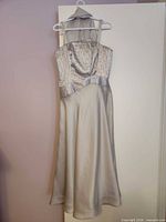 Front view of silver silk evening gown hanging on hanger