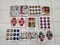 Overview of 12 boxed sets of assorted glass ornaments