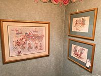 Corner view showing three framed prints with gold frames and green mats