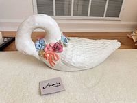 Full view of Austin Sculpture swan lying on side with brand card