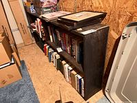 Front view of dark wood bookshelf filled with books, shows full length and three shelf structure