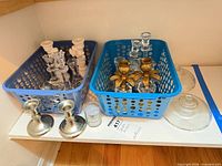 Overview of both baskets with assorted metal, crystal and glass candle holders on shelf