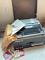 Typewriter with manual, power cord, bag and box visible