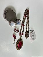 All jewellery pieces laid out: gold-tone necklace, matching earrings, silver-tone brooch and earrings