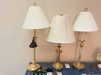 Three brass-tone table lamps with shades displayed together