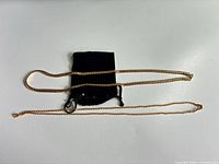Two gold-plated necklaces with pouch displayed
