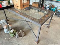 Overall view of metal patio table with glass insert and tile border showing construction and condition