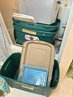 Stacked green totes with beige and blue lids and a clear tote inside