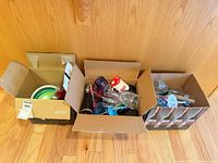 Three boxes showing plastic mixing bowls, travel mugs and assorted drinkware