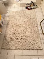 Full view of cream shag rug laid on tiled floor