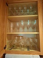 Cabinet interior showing three shelves filled with assorted glass stemware